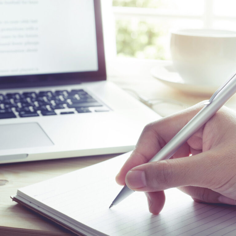 Mão de uma pessoa a escrever a sua carta de motivação num papel