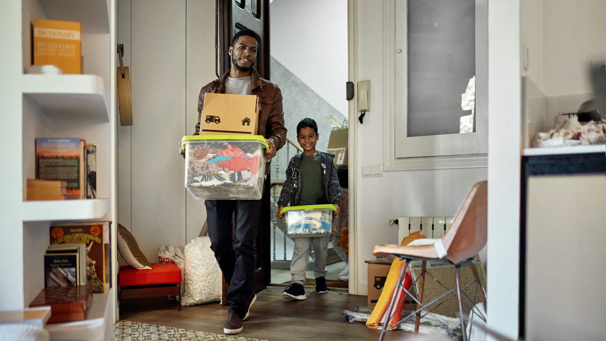 Pai e filho com caixas de cartão e de plástico nas mãos