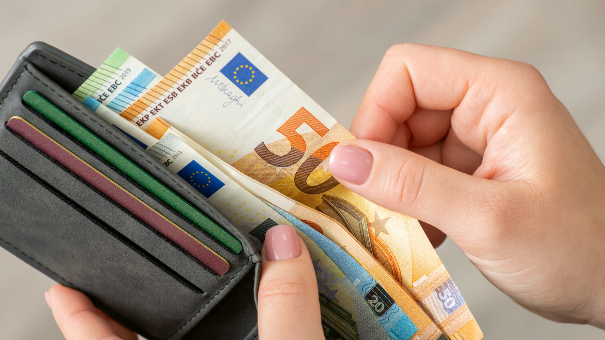 Pessoa a contar o dinheiro do salário líquido que recebeu em 2025